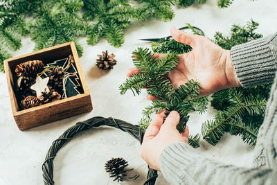Cropped hand of woman holding christmas decorations on table