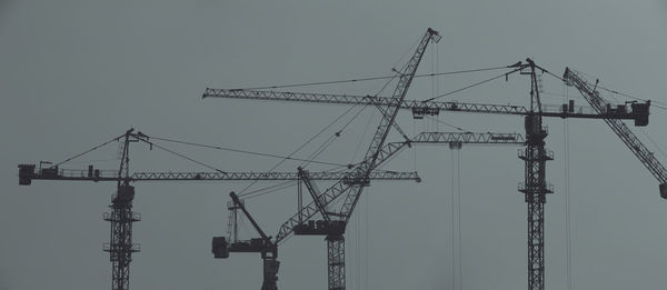 Low angle view of cranes against clear sky