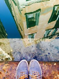 Low section of person wearing shoes by puddle with reflection