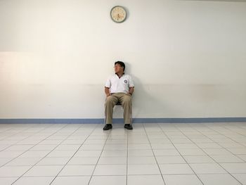 Full length of man sitting on wall