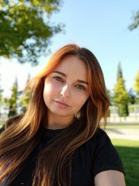 Portrait of beautiful young woman against trees
