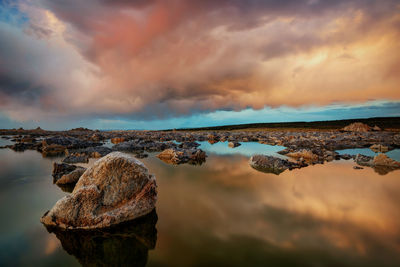Panoramic view of rocks on shore against sky during sunset