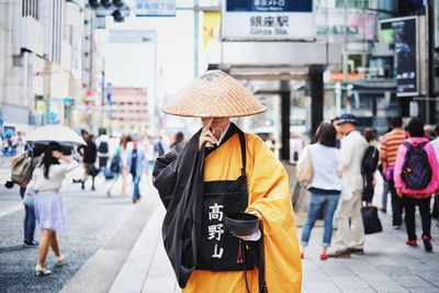 Monk standing on city street with people in background