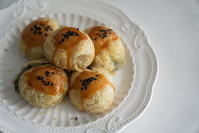 There are some delicious black sesame egg yolk pastries freshly baked on the plate on the table