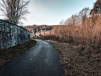 Road amidst bare trees against sky