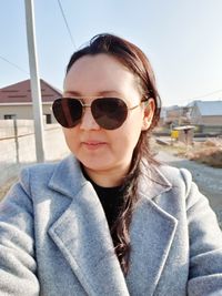 Portrait of young woman wearing sunglasses against clear sky