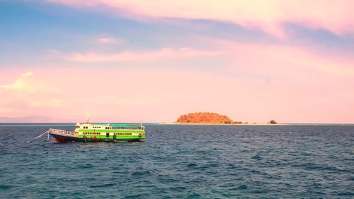 Boat in sea against sky during sunset