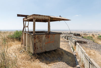 Rusty metallic structure on field against sky