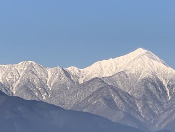 Scenic view of snowcapped mountains against clear blue sky