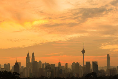 Buildings in city against cloudy sky during sunset