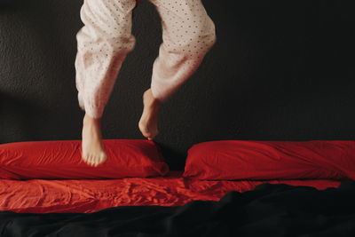 Low section of woman jumping on bed at home