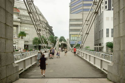 People walking on footpath amidst buildings in city