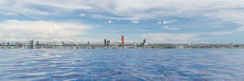 Infinity pool in city against cloudy sky