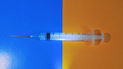 High angle view of syringe on colored background