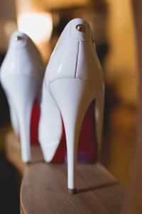 Close-up of white high heels on wooden table at home