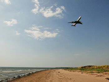 Low angle view of airplane flying over sea against sky