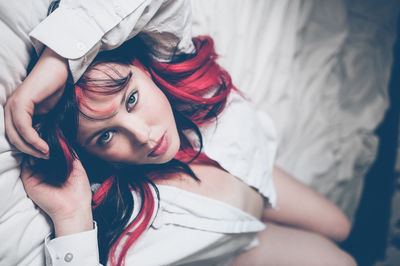 High angle portrait of young woman relaxing on bed at home