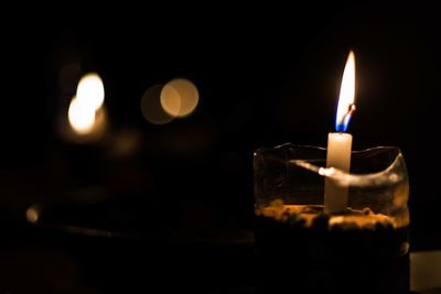 Close-up of lit tea light candle in dark room