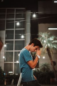 Side view of young man looking at illuminated building