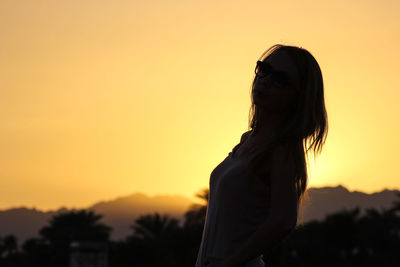 Woman standing against sky during sunset