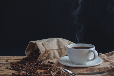 Close-up of coffee cup on table against black background