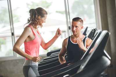 Male trainer training woman in gym