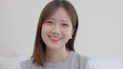 Portrait of young woman against white background