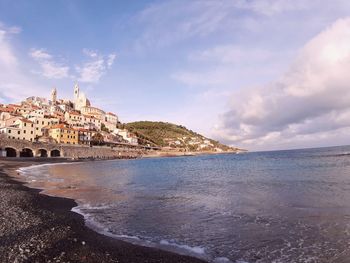 Buildings on beach against cloudy sky