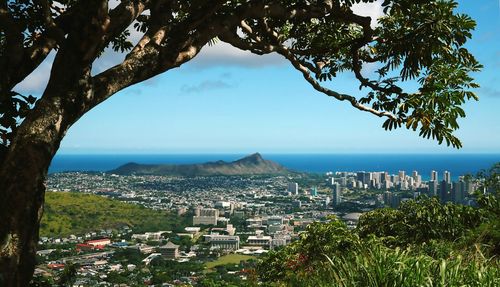 High angle view of cityscape and sea against blue sky