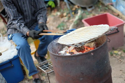 Low section of man preparing food on barbecue grill
