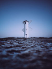 Lighthouse on sea against clear sky