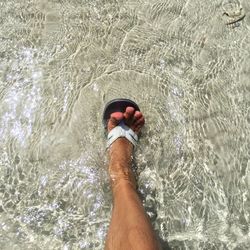 Low section of man wearing shoes over water