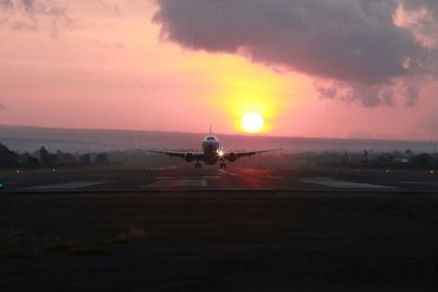 Airplane on runway against sky during sunset