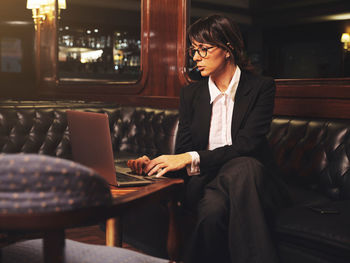 Mid adult man using mobile phone while sitting on table