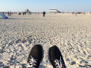 Low section of person wearing black shoes at beach