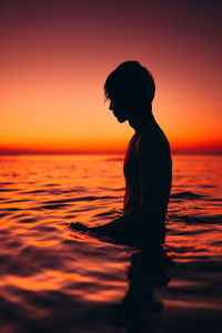 Silhouette woman against sea during sunset