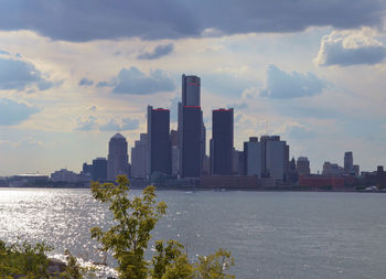 Sea by city buildings against sky