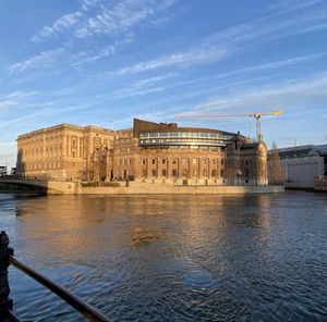 Buildings at waterfront against cloudy sky