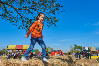 Pretty girl jumping over the hay stacks at a farm fair on halloween