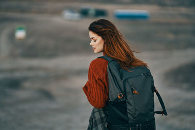 Young woman looking away while standing outdoors