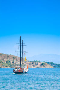 Sailboat sailing in sea against clear blue sky