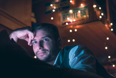 Low angle view of young man using mobile phone while sitting outdoors at night