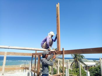 People working on railing against clear blue sky