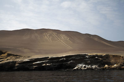 Scenic view of mountain by sea against sky