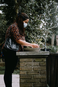 Side view of woman standing against trees