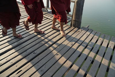 Low section of monks walking on wooden bridge