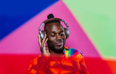 Portrait of young man standing against multi colored background