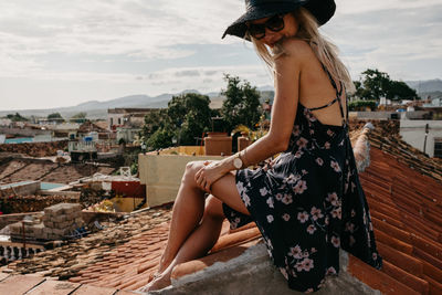 Young woman with arms outstretched against sky in city