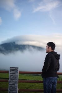 Side view of man looking away against sky