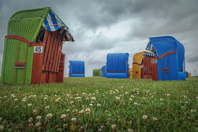 Multi colored hooded chairs on field against sky